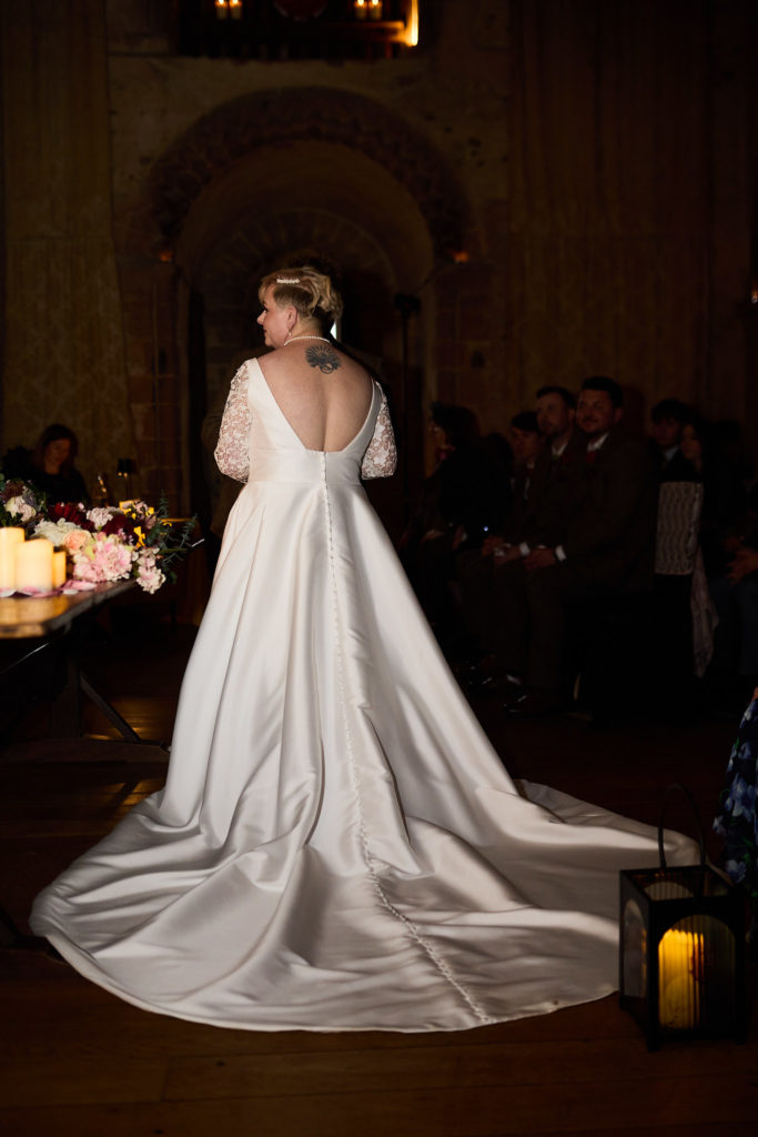 Bride from behind with her long dress train in the hall at Hedingham Castle