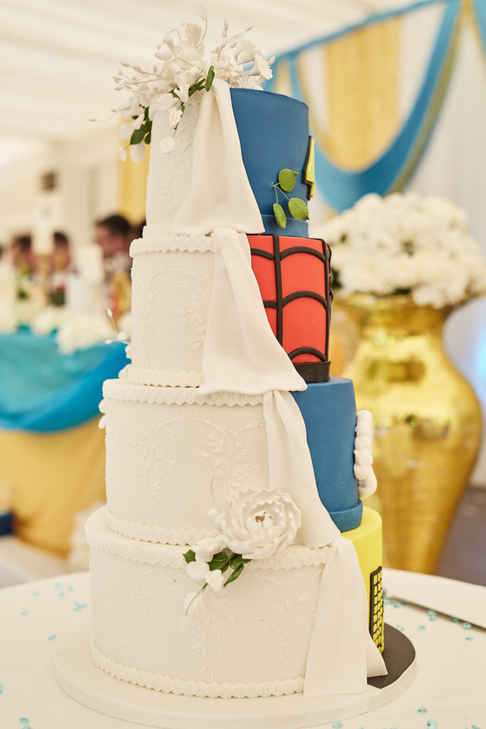 Five-tier wedding cake, half white with sugar flowers and half superhero themed