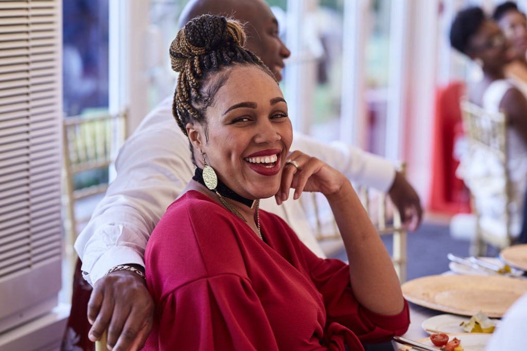 Wedding guest in a red dress laughing at the table