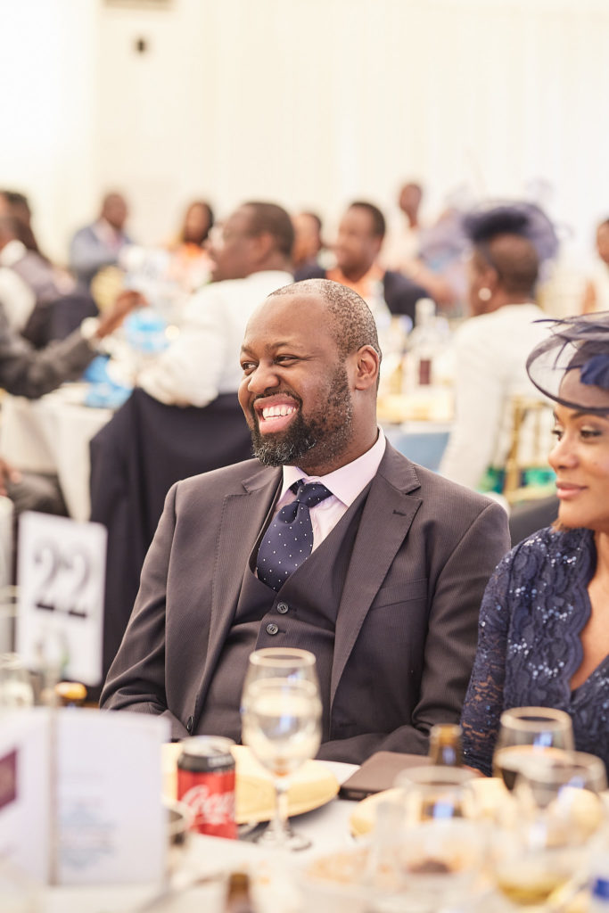Wedding guest in a waistcoat laughing during the speeches
