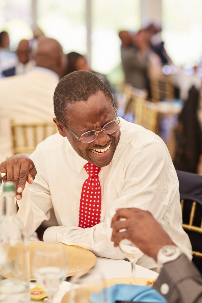Wedding guest in a red tie laughing during the speeches