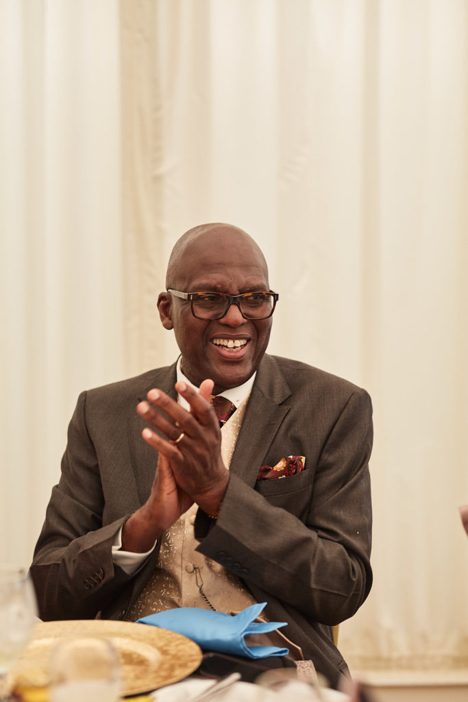 Older guest in a tweed jacket applauding during the speeches