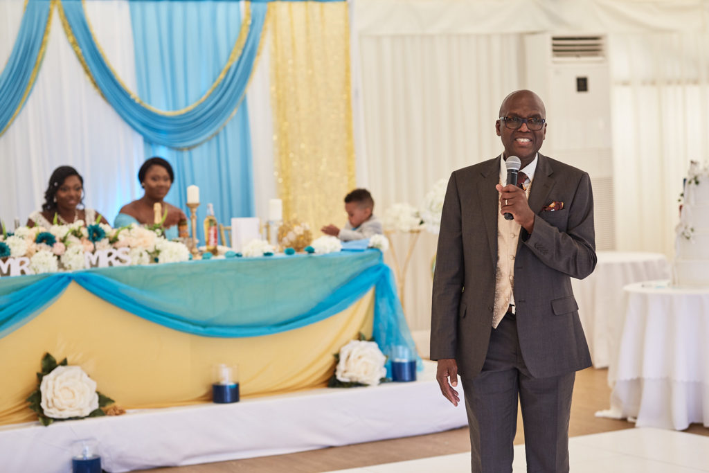 Man in a suit giving a speech with a microphone in front of the top table