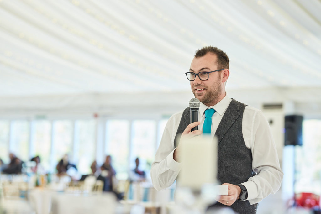 Best man reading his speech in a waistcoat and teal tie