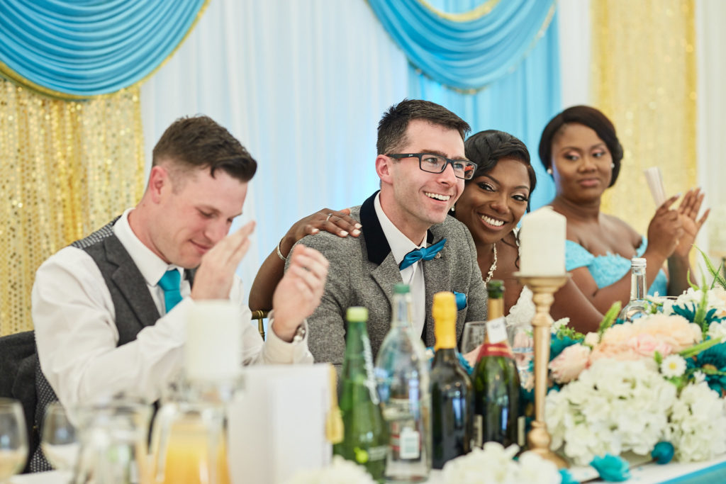 Groom covering his face as he laughs at the top table during the speeches