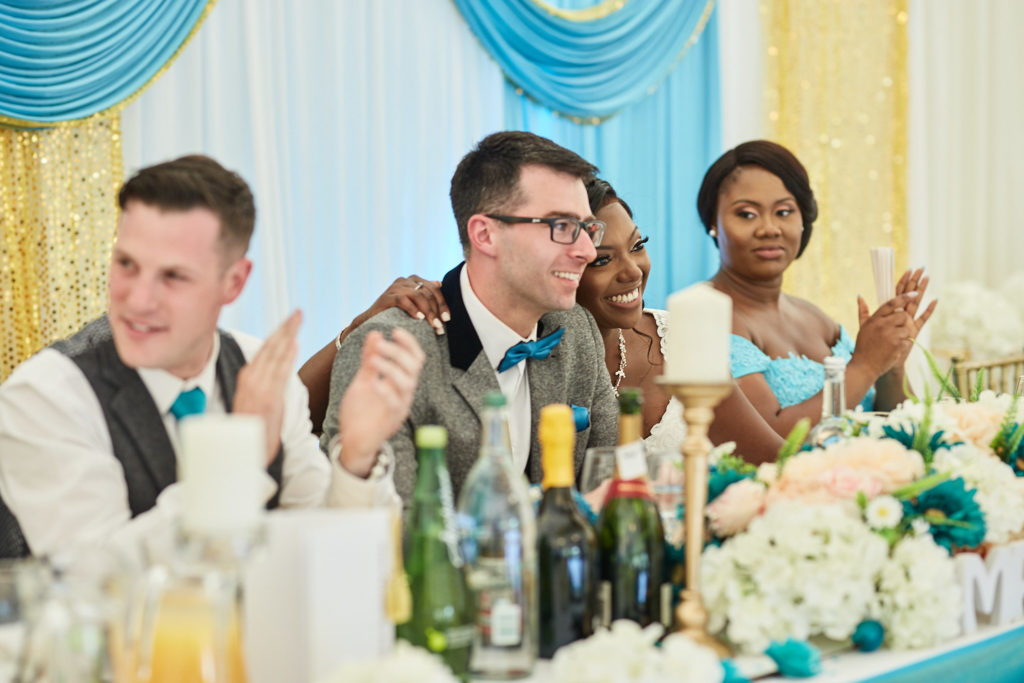 Groom and best man laughing at the top table beside the bridesmaids