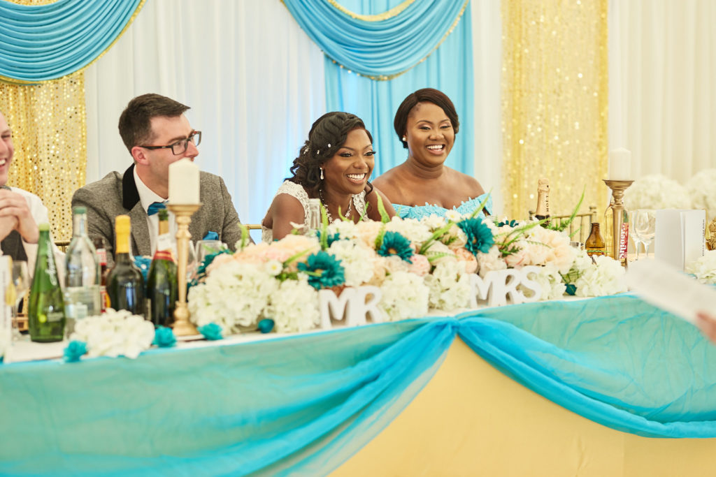 Bride and groom at the top table decorated with white and teal flowers