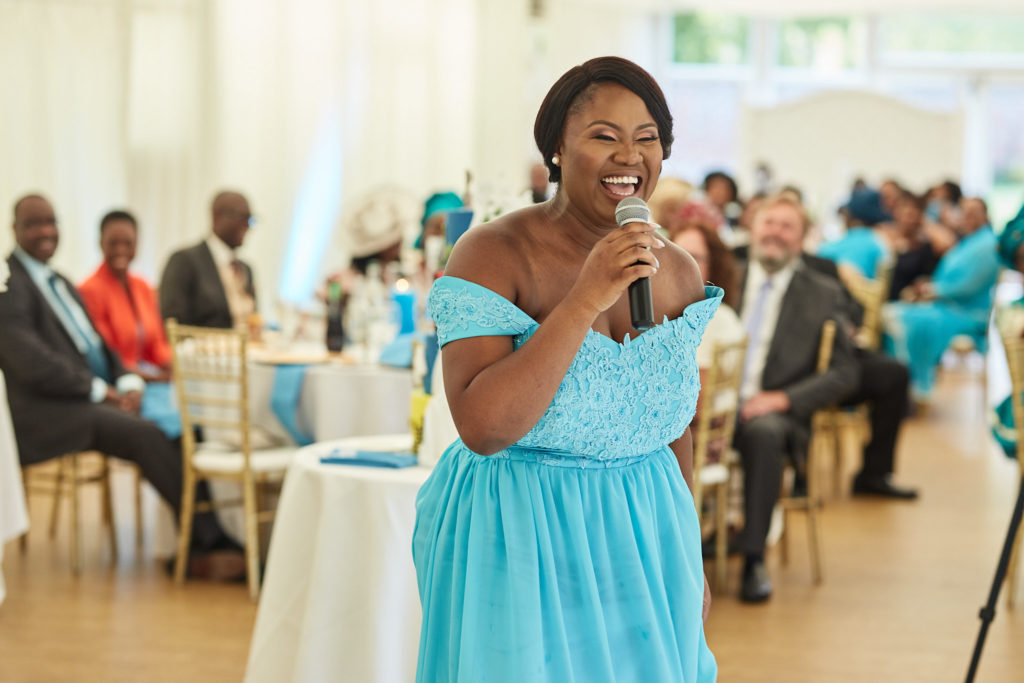 Bridesmaid in a turquoise dress giving a speech with a microphone