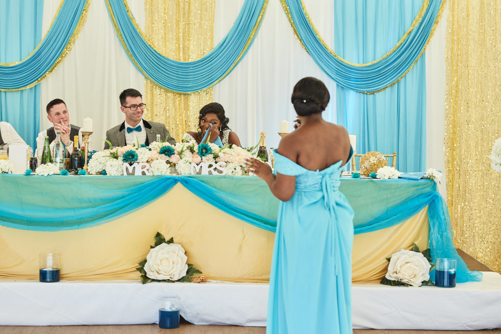Bridesmaid giving her speech to the bride and groom, seen from behind