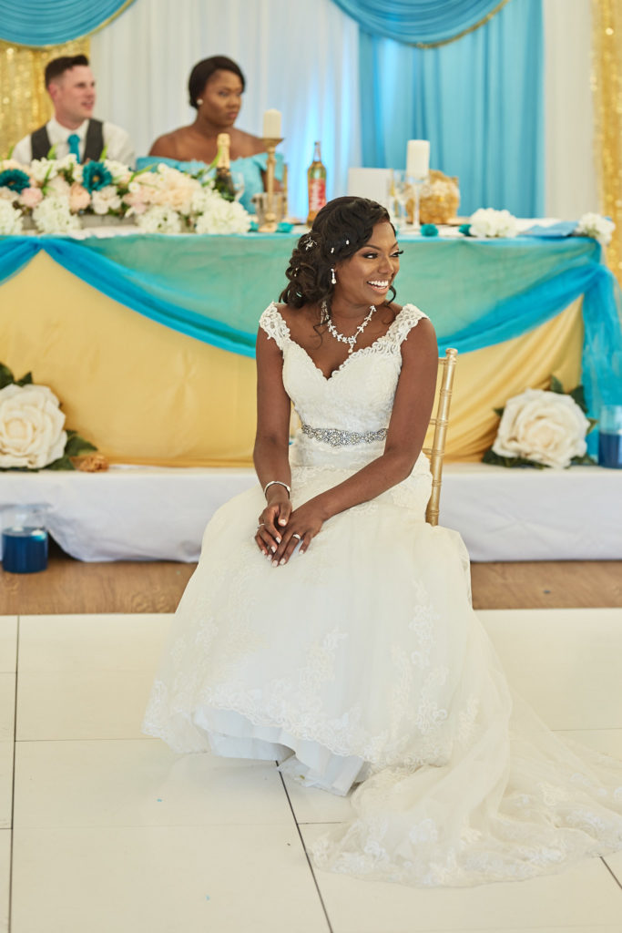 Bride sitting on the dance floor in her lace wedding dress, smiling