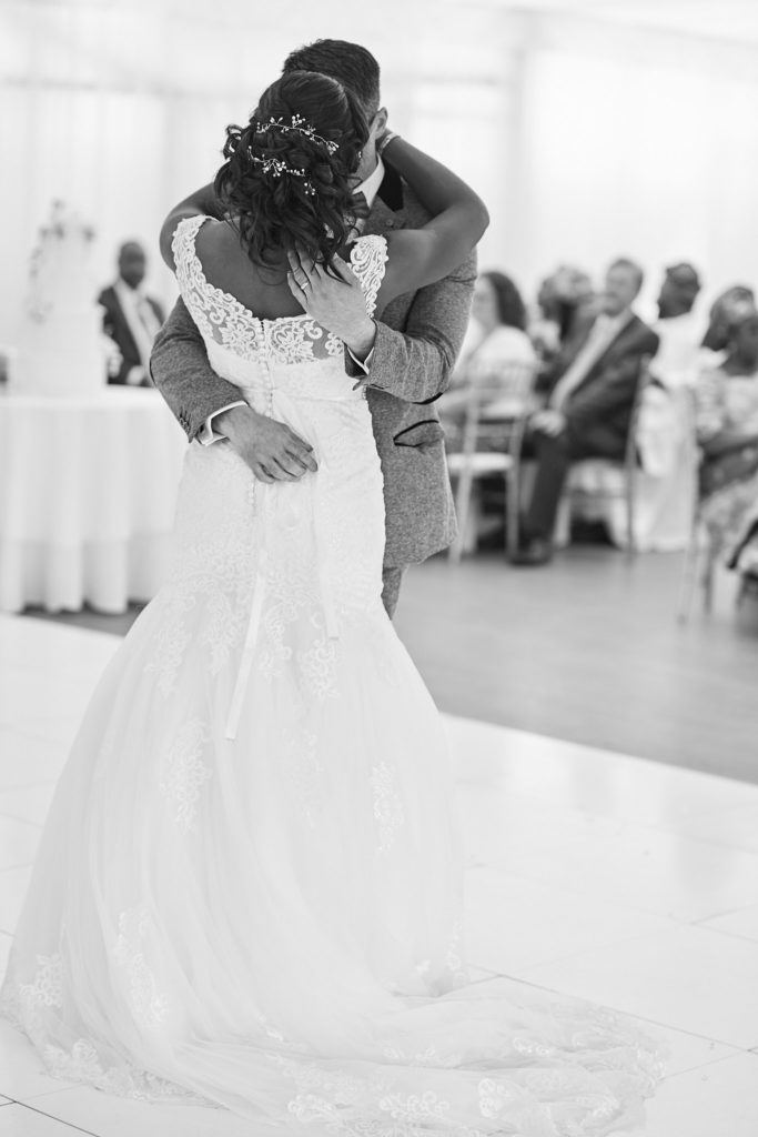 Black and white photo of the bride from behind in the groom's arms during the first dance