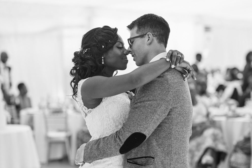 Black and white photo of the bride and groom smiling at each other during the first dance