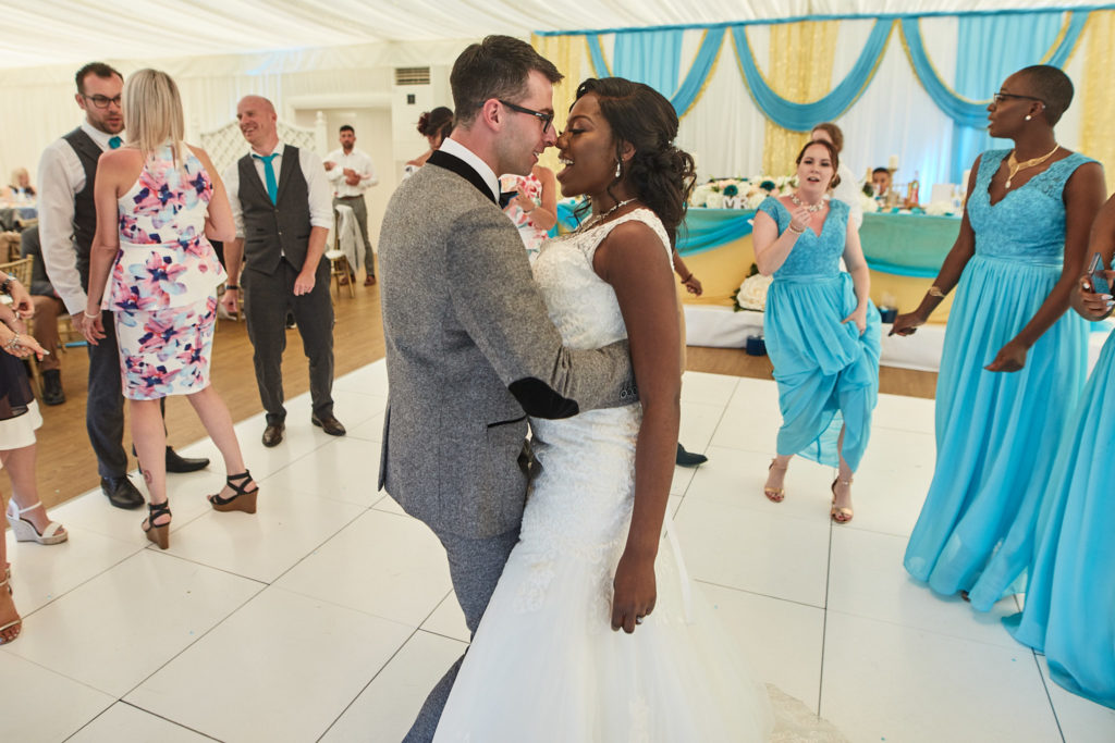 Bride and groom dancing as bridesmaids in turquoise join them on the dance floor
