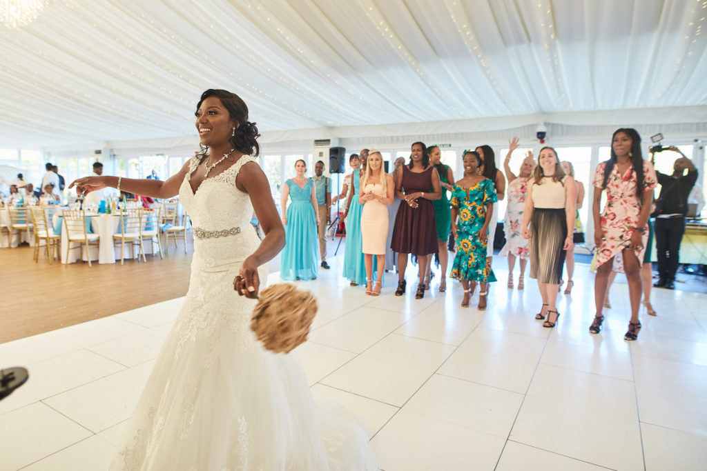 Bride about to throw her bouquet to guests lined up behind her