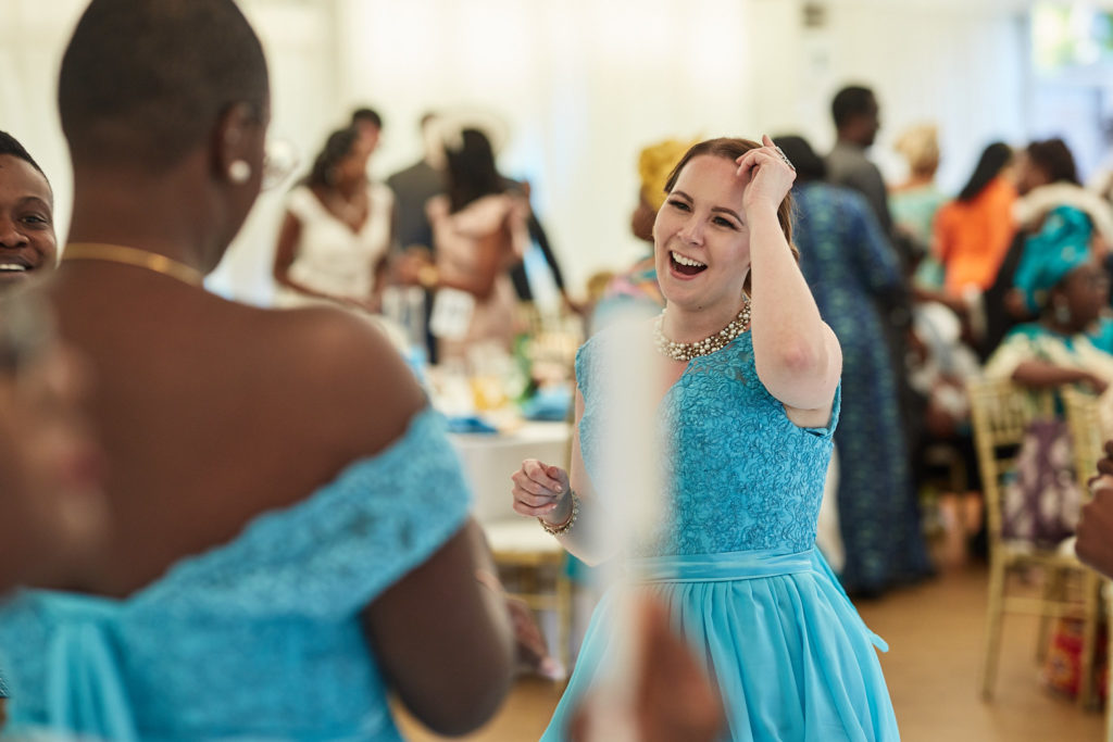 Wedding guest in a turquoise dress laughing on the dance floor