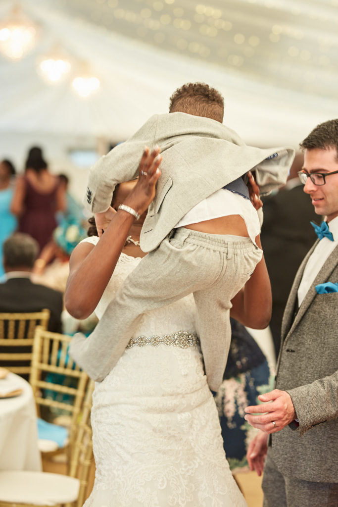 Bride lifting a young page boy into the air beside the groom