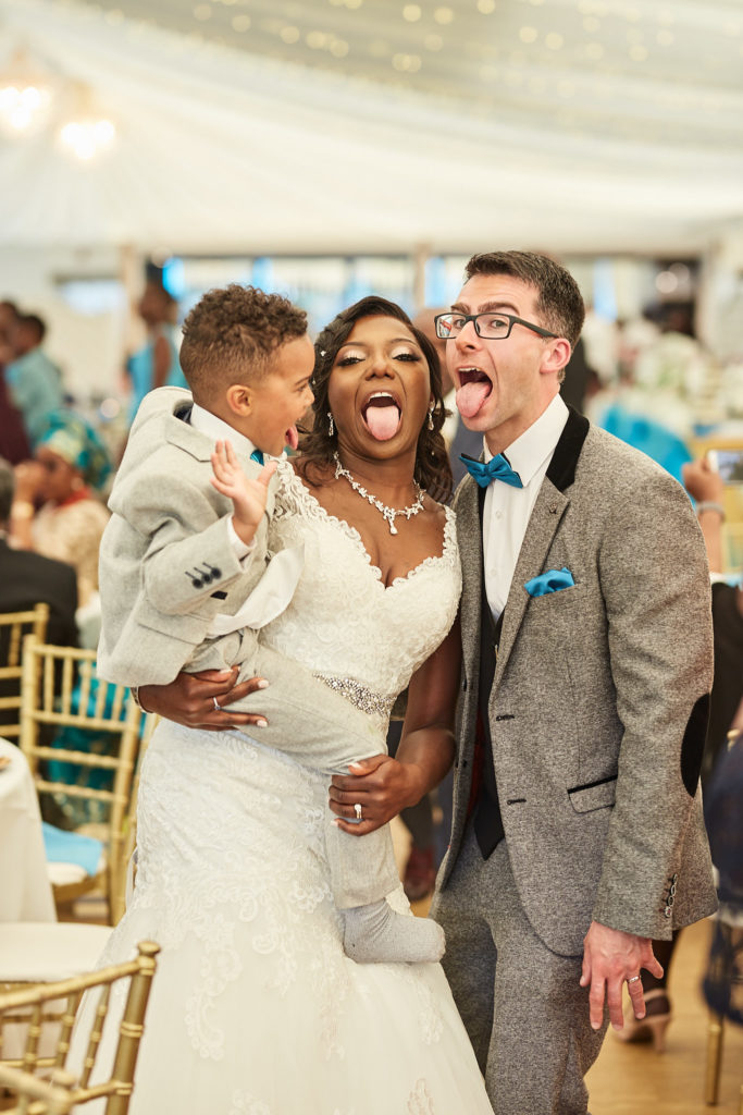Bride and groom pulling funny faces with a young page boy