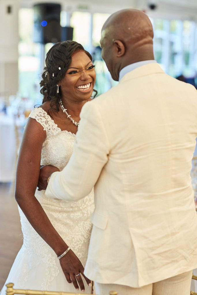 Bride laughing as she dances with a man in a cream suit