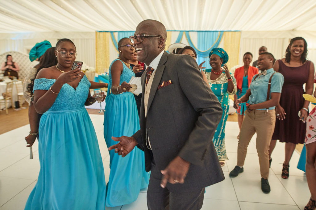 Older guest dancing with bridesmaids in turquoise dresses