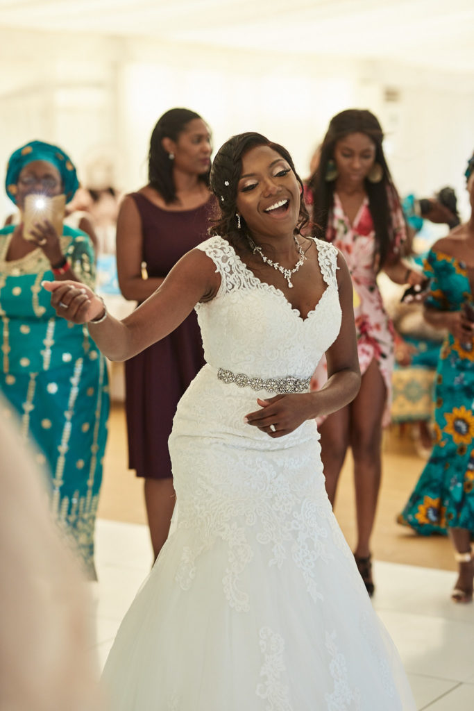 Bride dancing in her lace wedding dress surrounded by guests