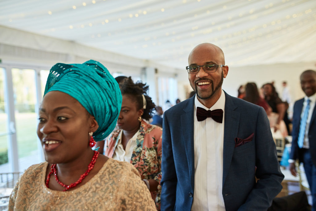 Guest in a teal head tie laughing beside a man in a bow tie