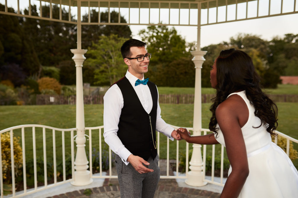 Bride and groom holding hands in the bandstand at Quendon Hall