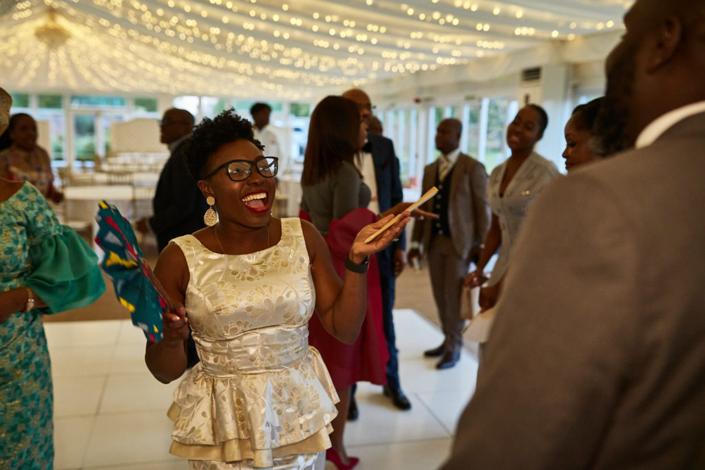 Guest in a cream lace dress laughing under fairy lights