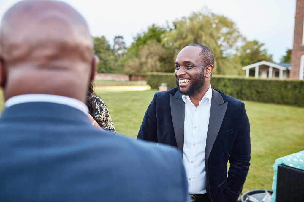 Wedding guest in a navy jacket laughing on the lawn