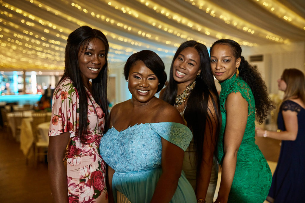 Four wedding guests posing together under fairy lights