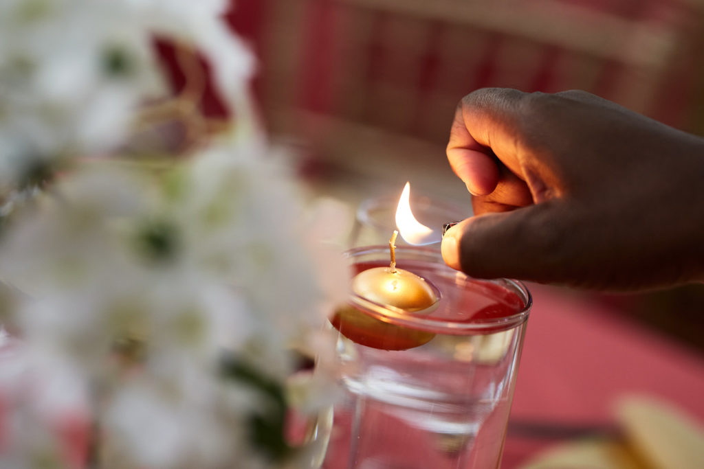 Hand lighting a floating candle beside white flowers