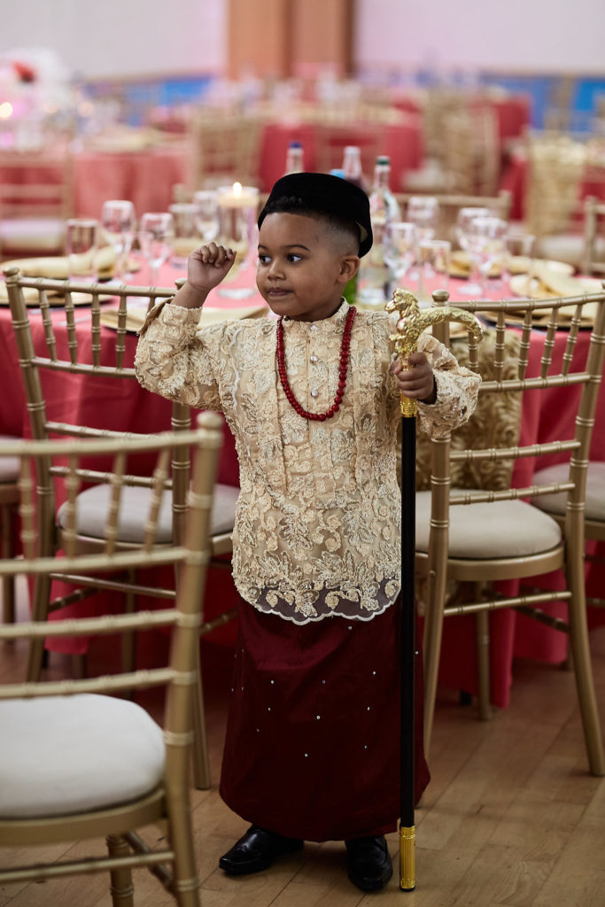 Young boy in traditional Itsekiri dress with a hat, coral beads and a walking stick