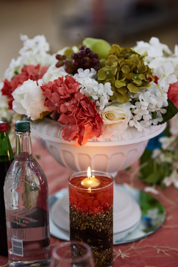 Table centrepiece of red and white flowers with a floating candle