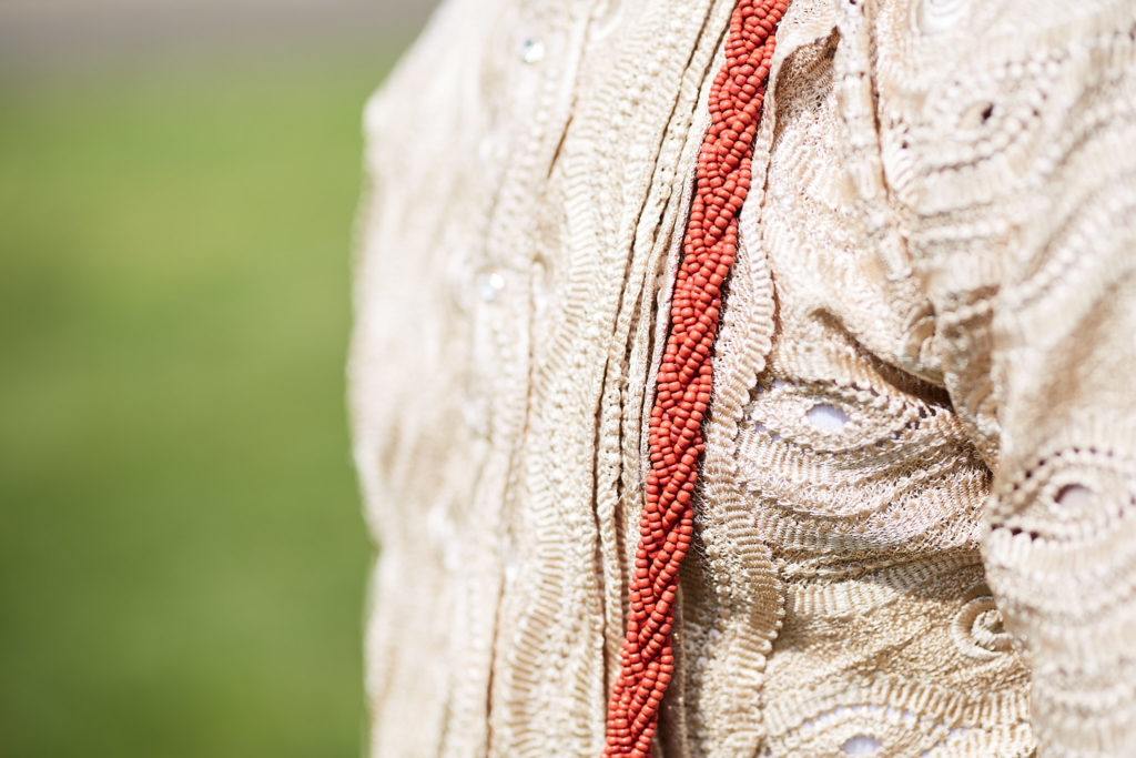 Close-up of coral beads against a cream lace traditional shirt