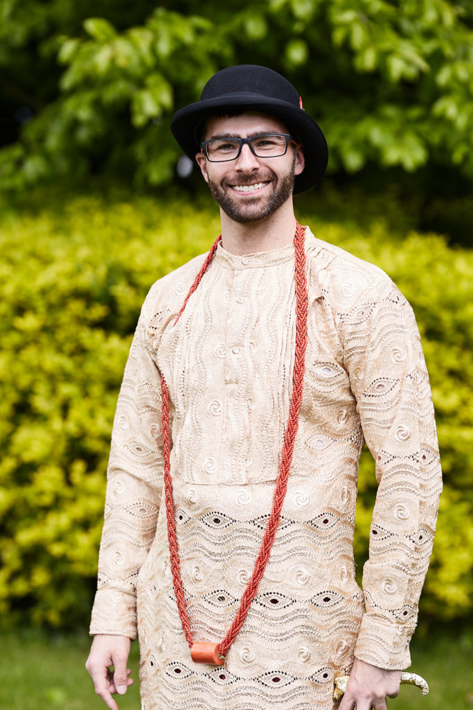 Groom smiling in traditional Itsekiri dress with a bowler hat and coral beads