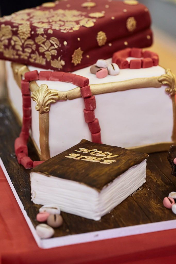 Wedding cake shaped like a stack of traditional gift boxes with coral beads and a book