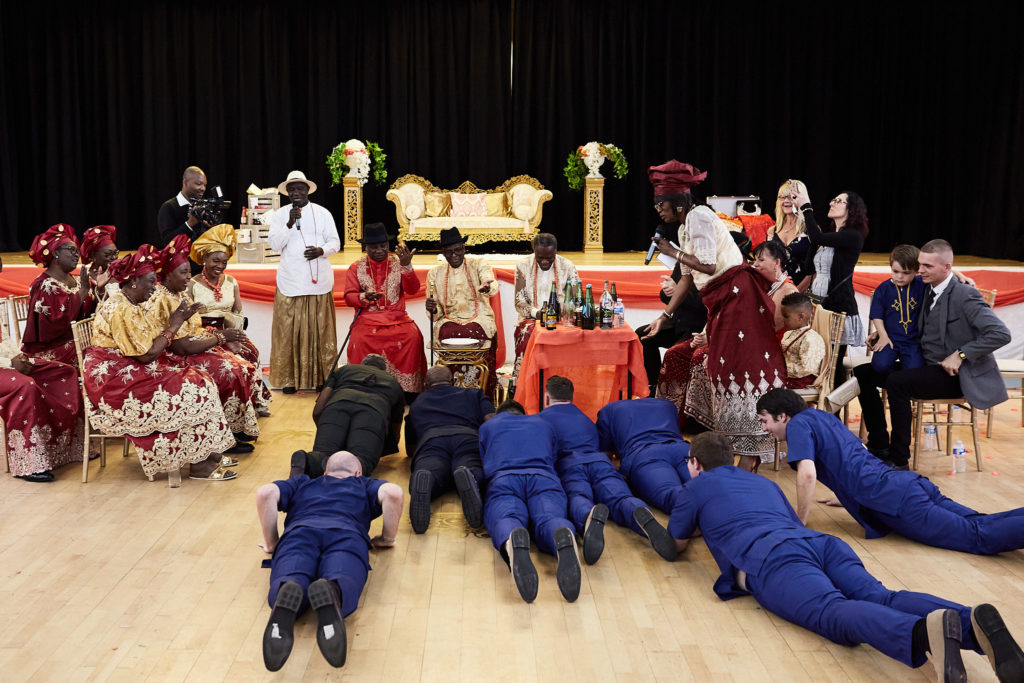 Groomsmen in blue lying face down on the floor in front of the elders during the ceremony