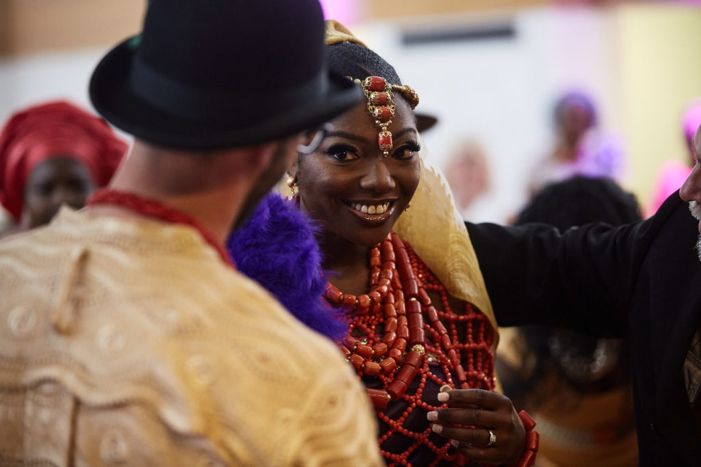 Bride in coral beads smiling at the groom during their traditional Itsekiri wedding