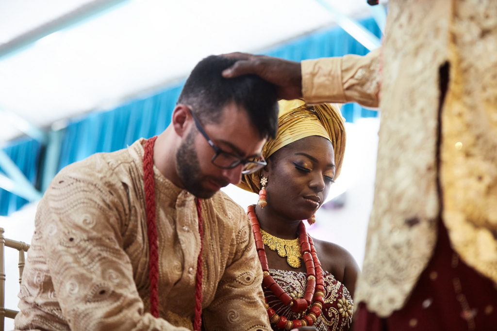 Elder blessing the kneeling bride and groom with a hand on the groom's head