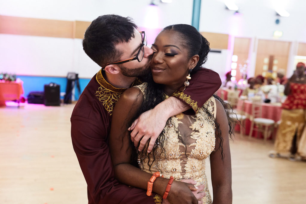 Groom kissing the bride's cheek as he hugs her from behind