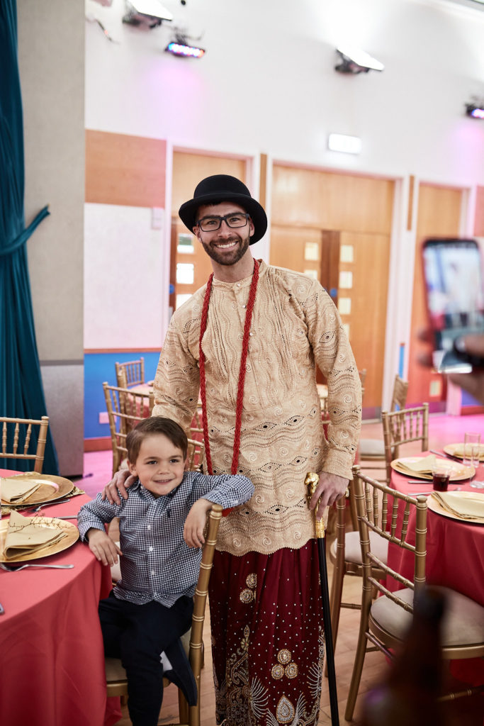 Groom in traditional dress and bowler hat standing with a young boy