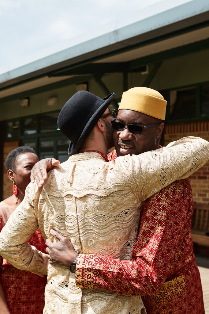 Groom hugging a guest in traditional dress outside the hall