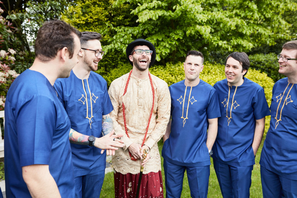 Groomsmen in blue tunics laughing with the groom