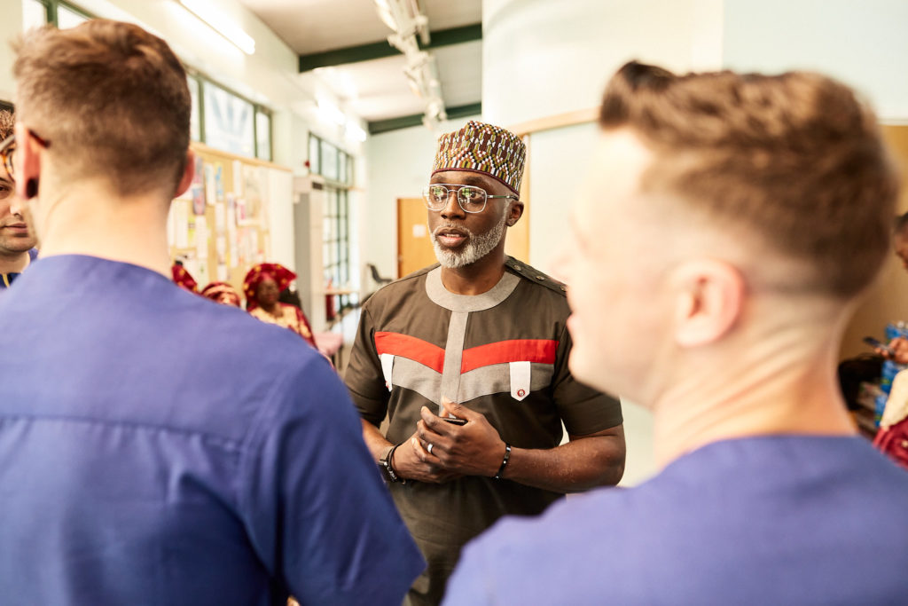 Guest in a traditional cap chatting with the groomsmen