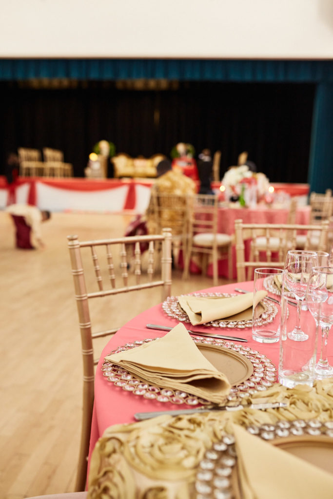 Tables set with gold napkins and gold chairs in front of the stage