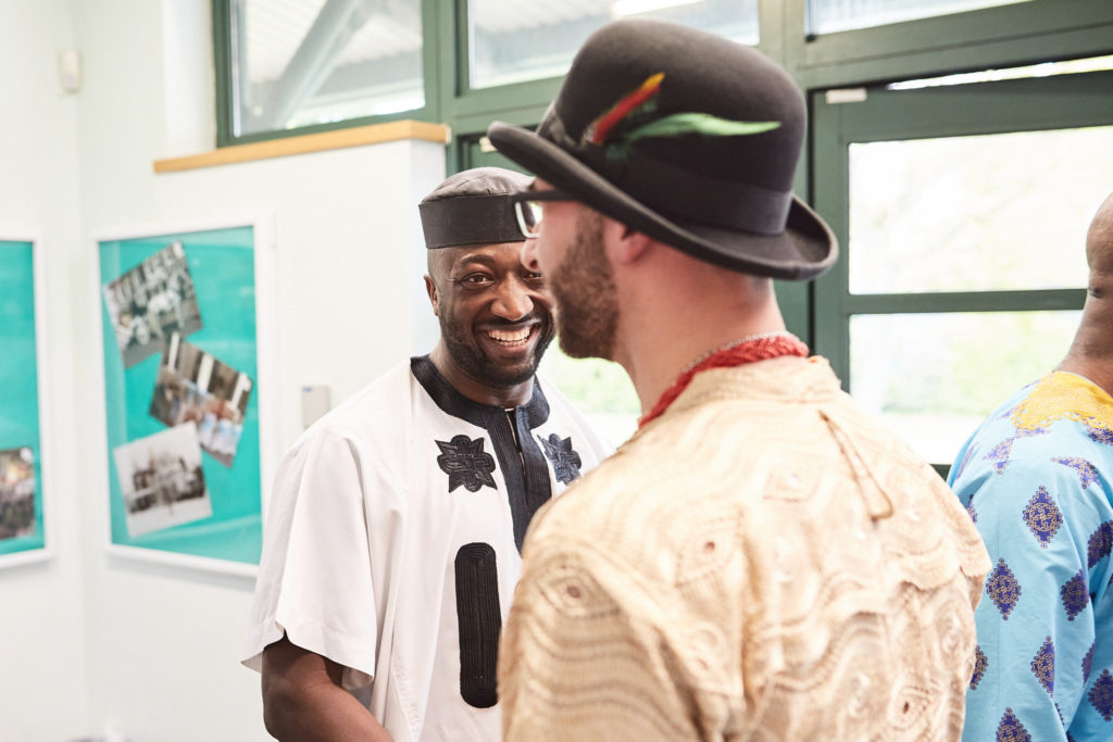 Groom in his bowler hat laughing with a guest