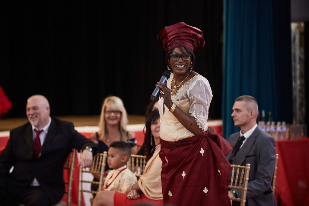 Woman in traditional dress speaking with a microphone during the ceremony