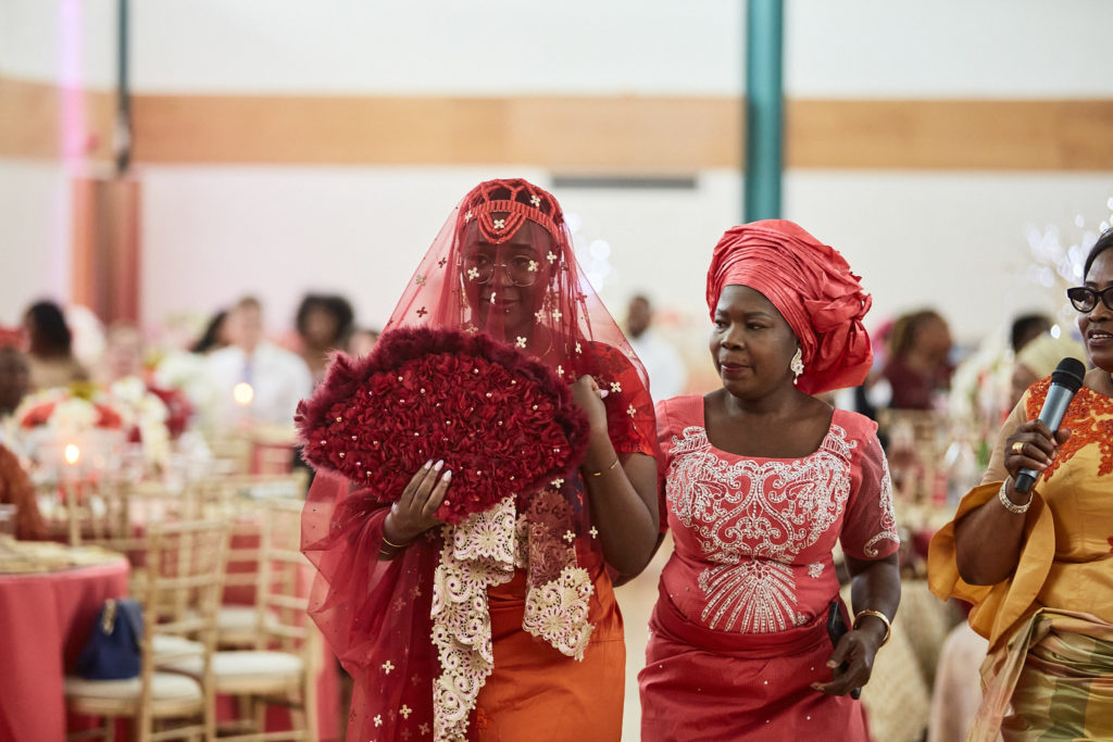 Veiled bride arriving with a woman in red traditional dress