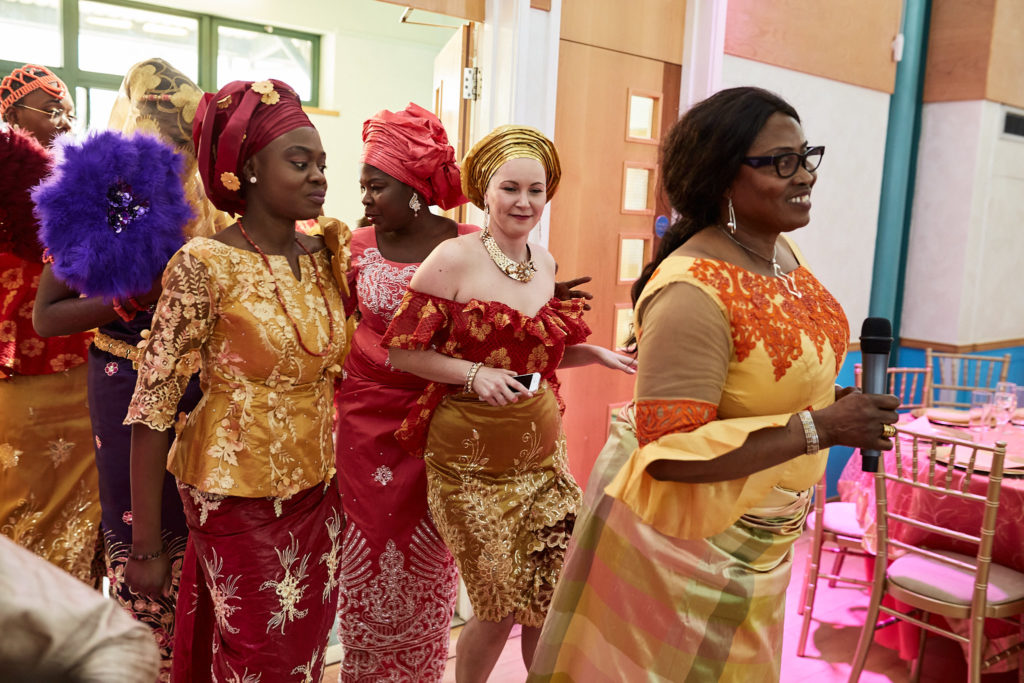 Women in red and gold traditional dress dancing into the hall