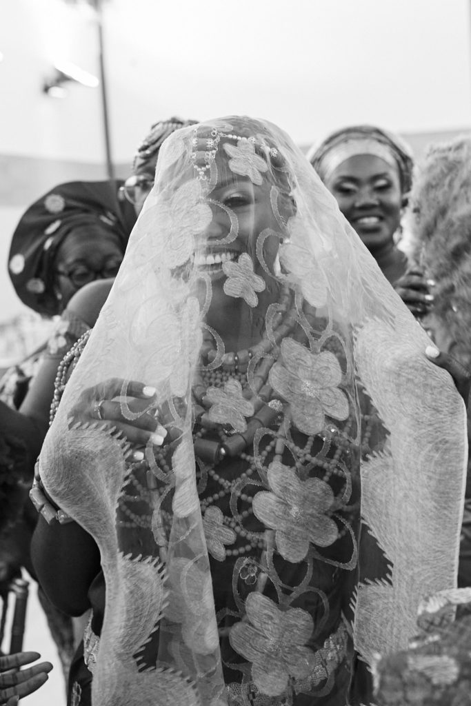 Black and white photo of the bride smiling beneath a lace veil