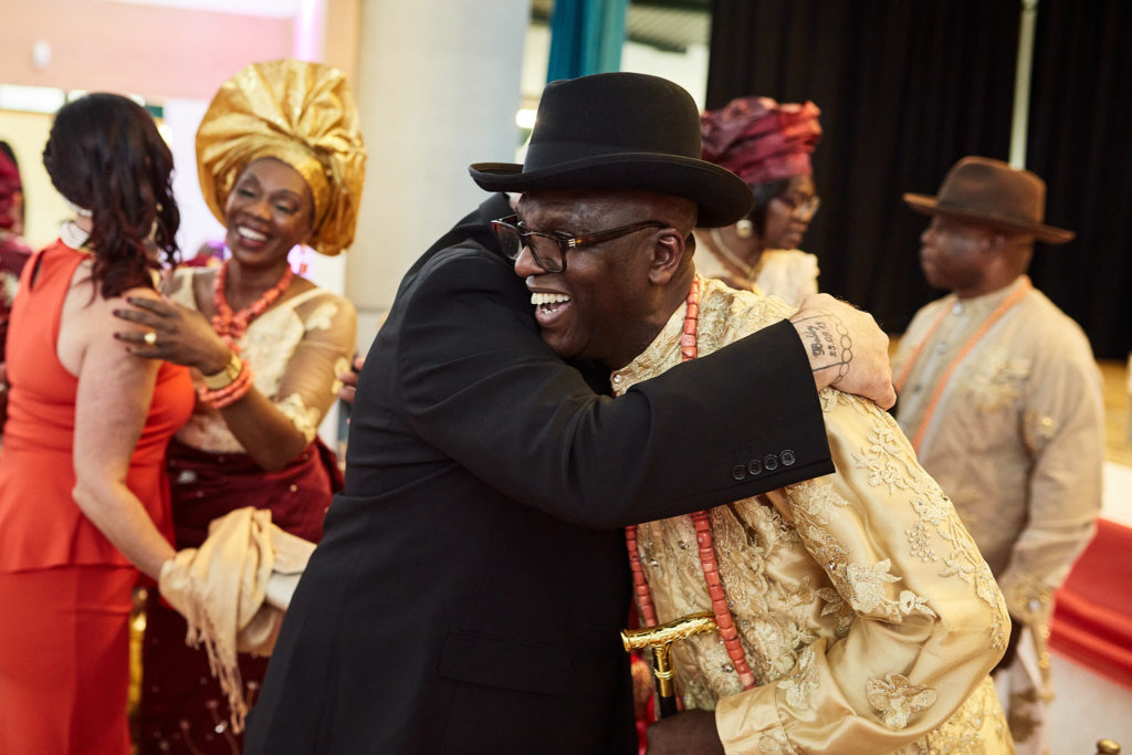 Elder in a black hat hugging the groom